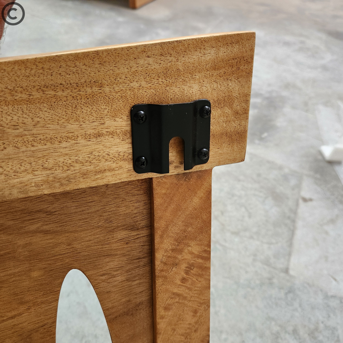 Détail du système de fixation en métal noir sur une tête de lit en manguier massif – finition artisanale et robustesse Kukuu.