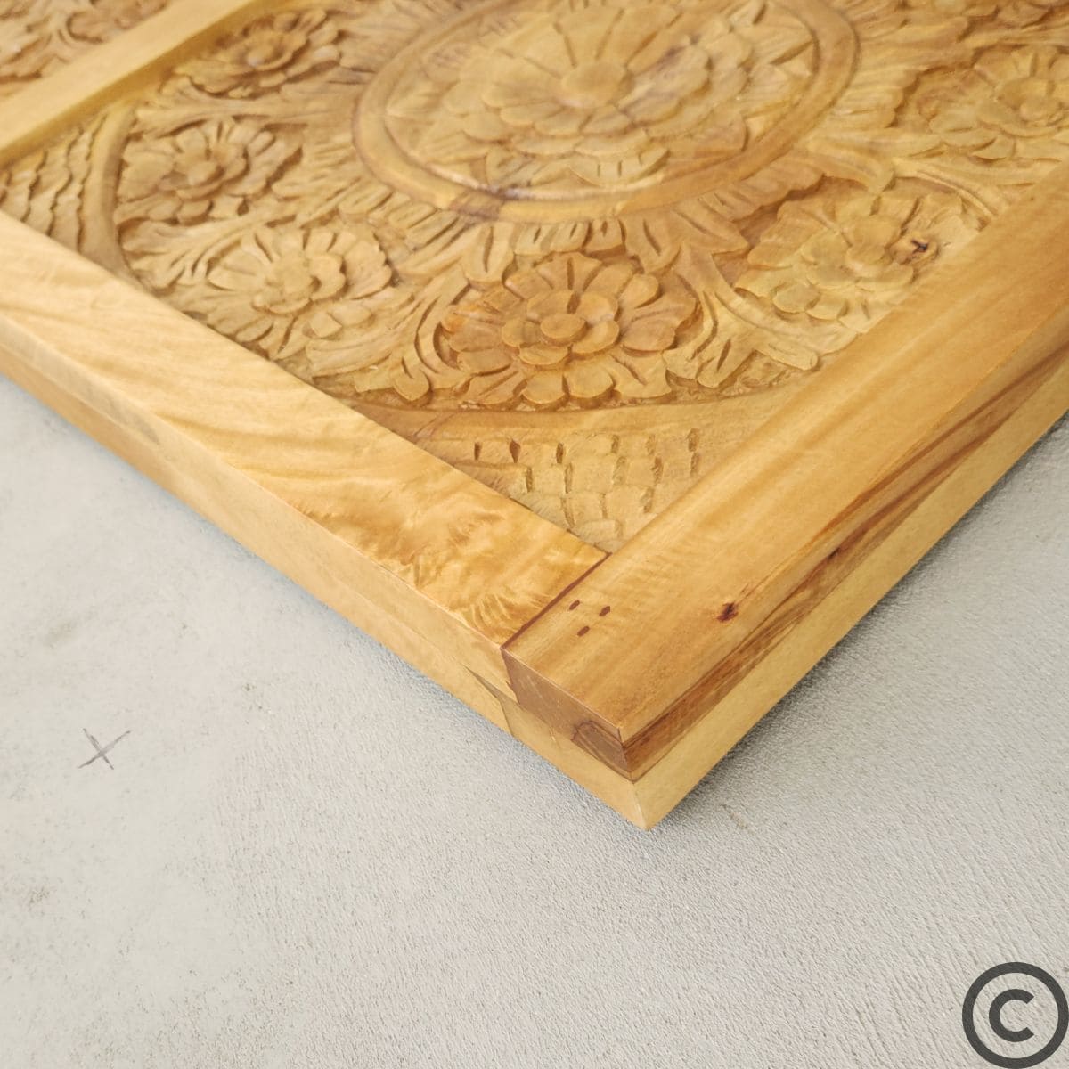 Zoom sur les motifs sculptés et la texture naturelle du bois d’une tête de lit artisanale KUKUU.