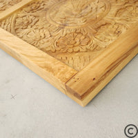 Zoom sur les motifs sculptés et la texture naturelle du bois d’une tête de lit artisanale KUKUU.