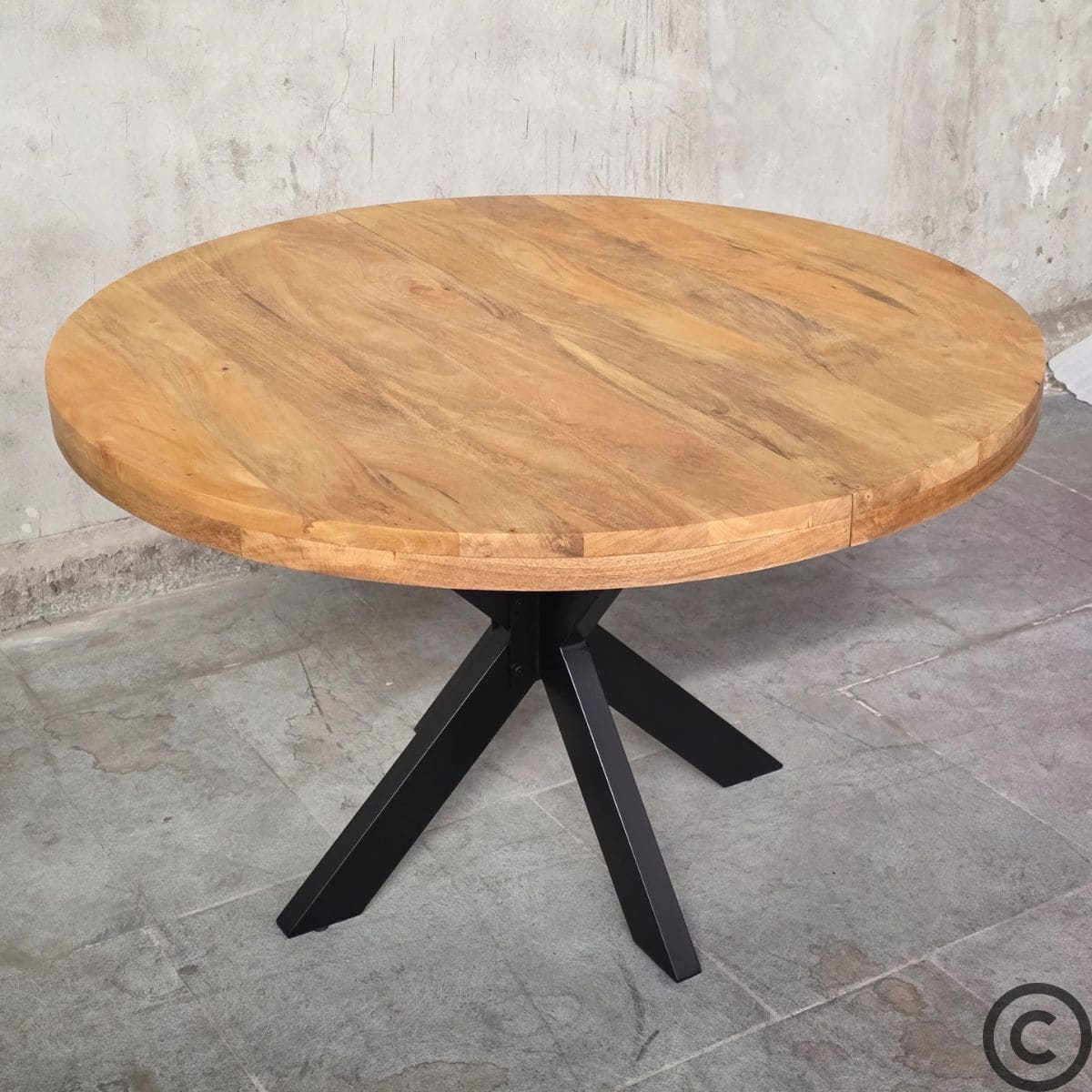 Table ronde extensible industrielle vue de biais avec plateau en bois massif de manguier