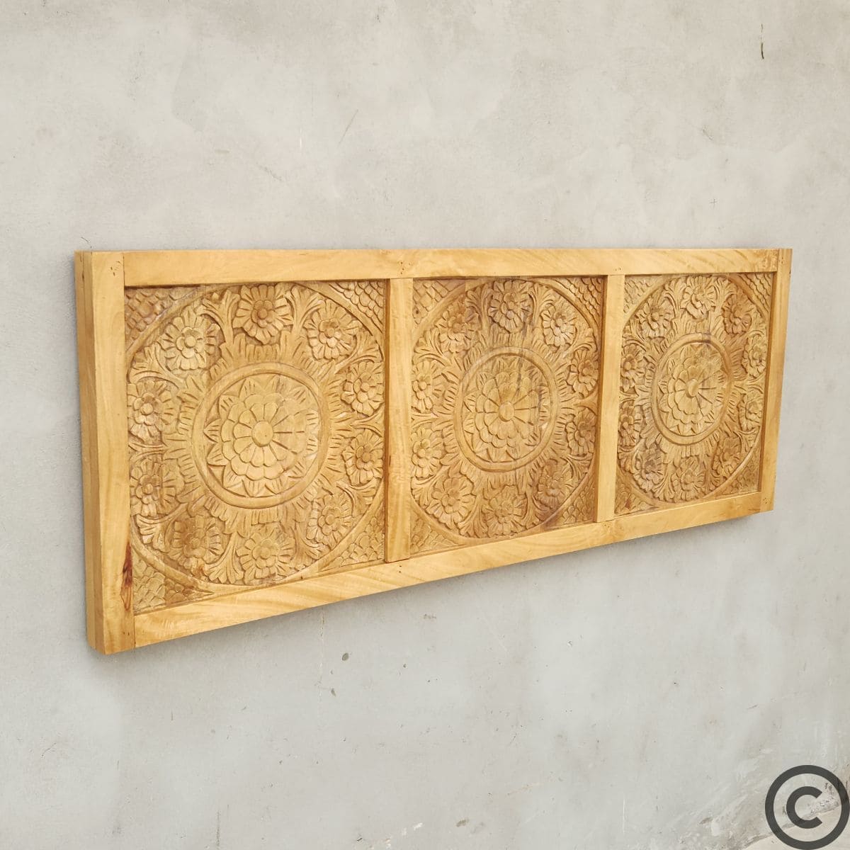 Tête de lit artisanale KUKUU en manguier massif, vue de biais mettant en valeur le relief sculpté à la main.