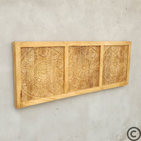 Tête de lit artisanale KUKUU en manguier massif, vue de biais mettant en valeur le relief sculpté à la main.