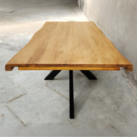 Table à manger extensible KUKUU en bois de manguier aux bords naturels et pieds croisés en métal noir, parfaite pour un intérieur industriel.