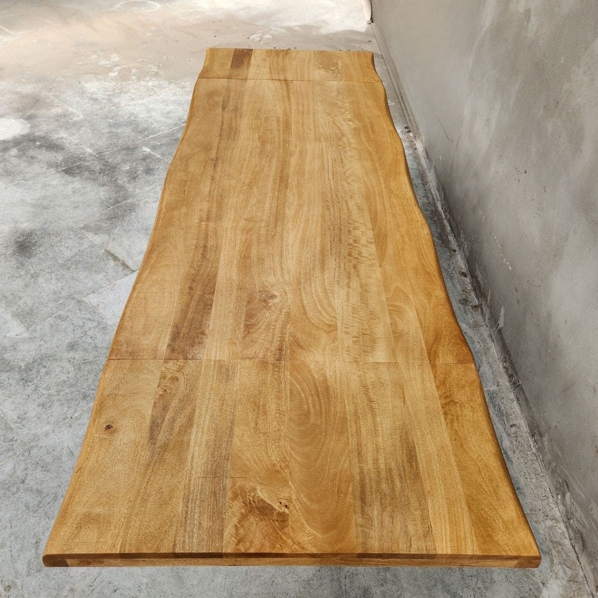 Plateau en bois de manguier massif KUKUU, au bord naturel et teinte miel. Un design unique pour votre table extensible industrielle.