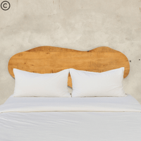 Tête de lit en manguier massif forme organique installée derrière un lit double – design naturel et chaleureux pour chambre moderne Kukuu.